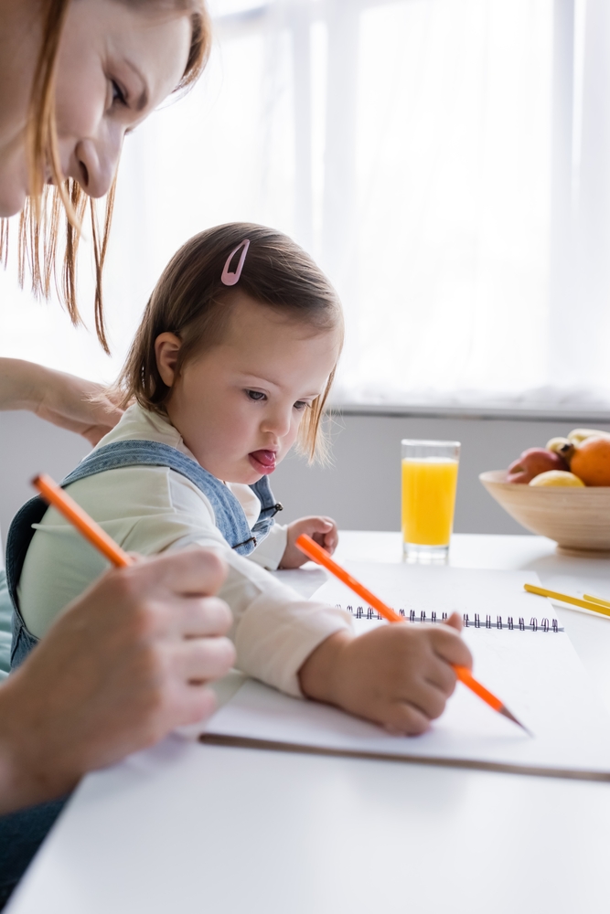 a young child with Down Syndrome learning to write. 