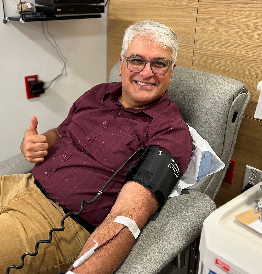 A person donating blood smiles as he gives a thumbs-up.