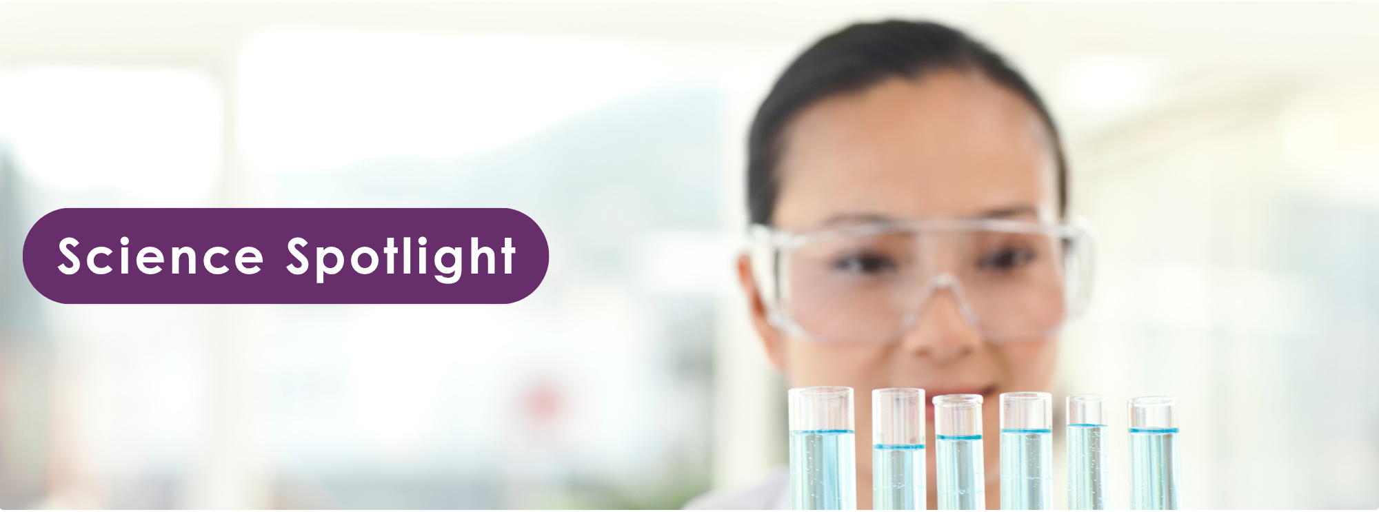 Photograph of a scientist wearing safety goggles standing behind a row of test tubes filled with blue liquid, highlighting a laboratory setting. Purple label with white text 