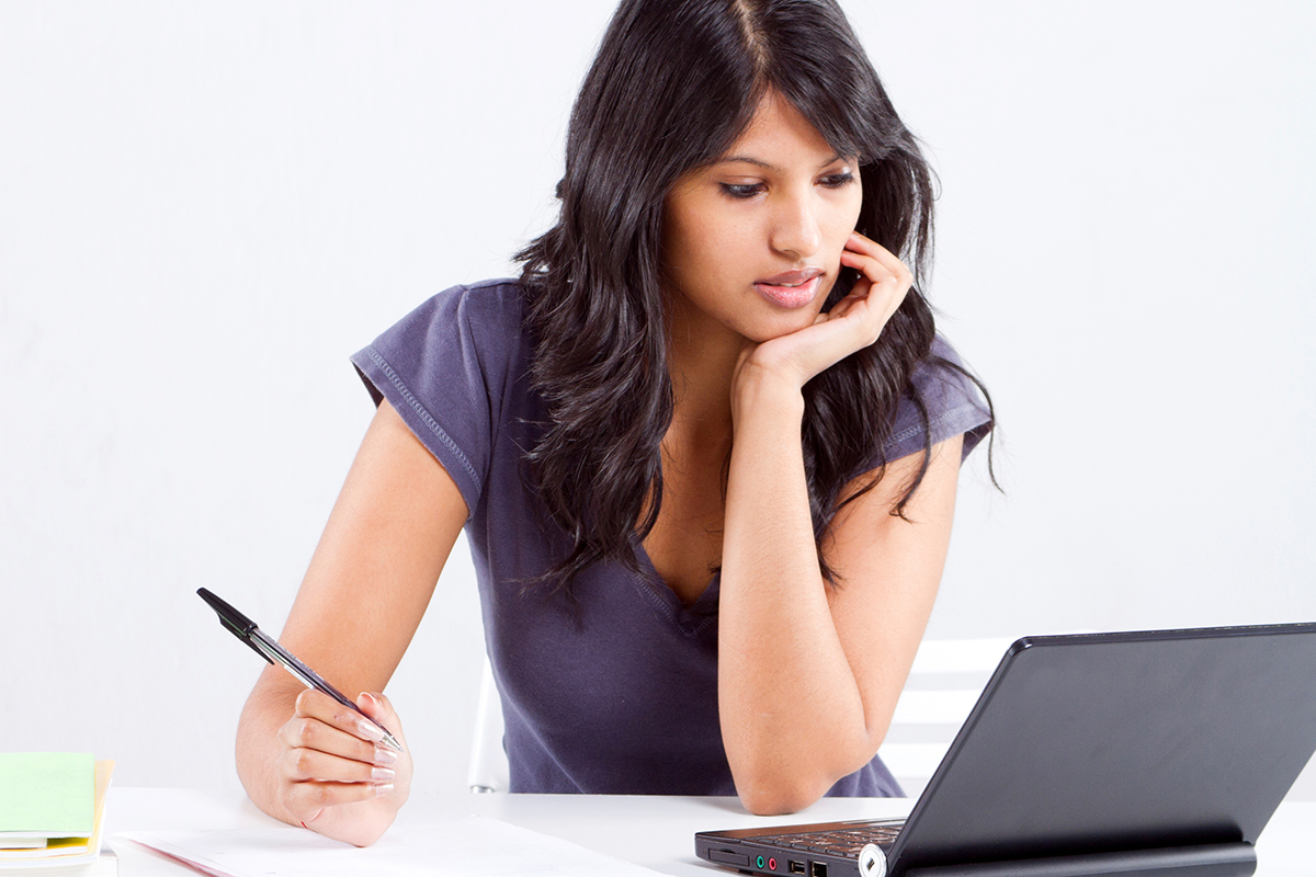 Close-up of a woman with a laptop and a writing pad