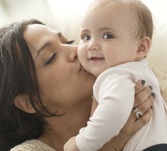 A mother kisses her baby's cheek.