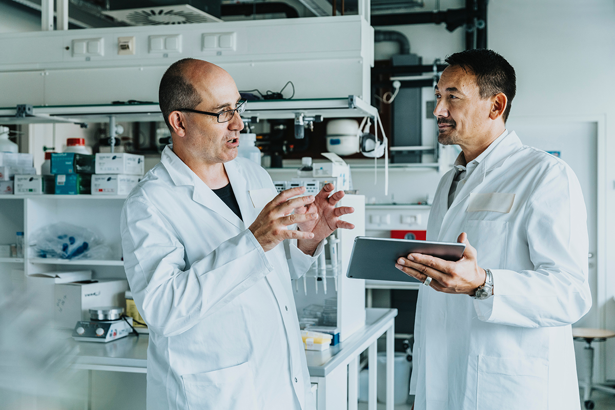 Scientists having discussion while using digital tablet at laboratory