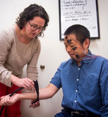 Dr. Lauren Atlas (NCCIH, NIMH, NIDA) applies a thermal heat probe to a volunteer wearing facial electromyography electrodes to measure nonverbal responses to painful stimulation.