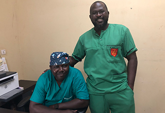 Photo of Colonel Sanou and Colonel Nacanabo in smiling while wearing scrubs