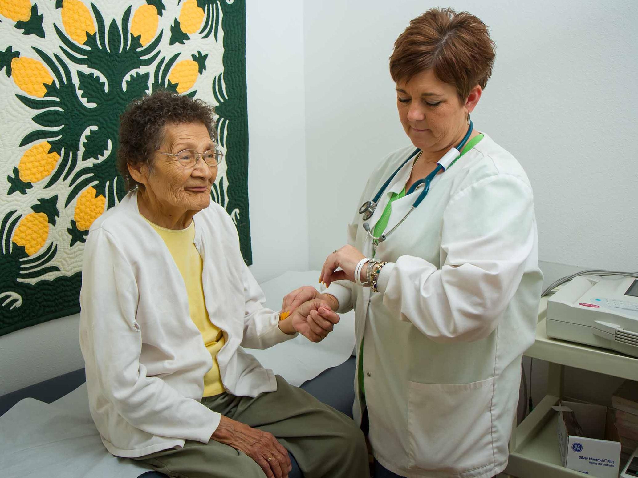 Medical professional measuring heart rate of elderly female patient