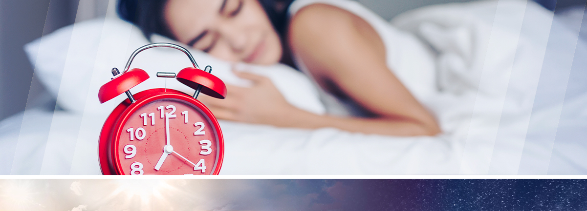 Decorative. Red alarm clock. A woman can be seen out of focus sleeping in the background.