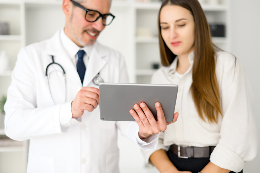 Male doctor and female patient looking at a tablet.