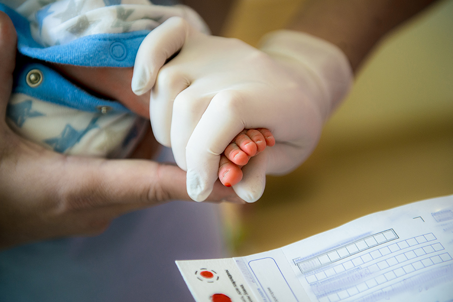Doctor takes blood from a newborn’s foot for testing.