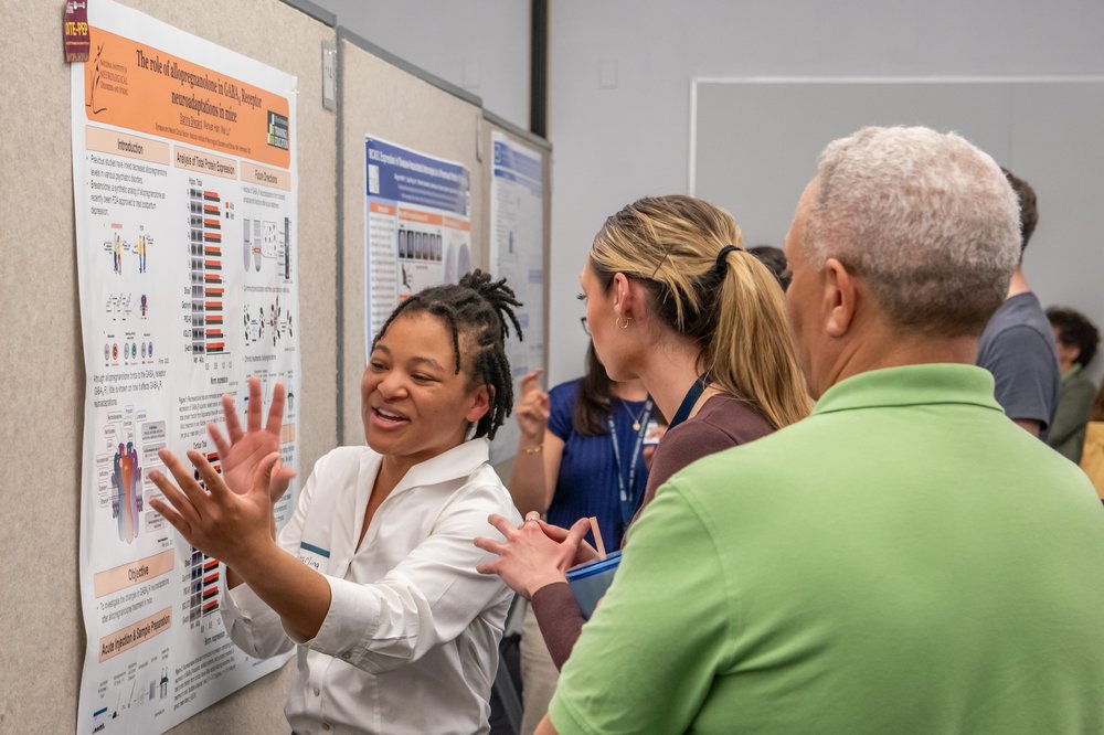 A trainee explaining the content of their poster to OITE Career Counselor John Taborn
