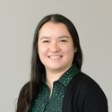Headshot of a woman with black hair, a green shirt and black cardigan