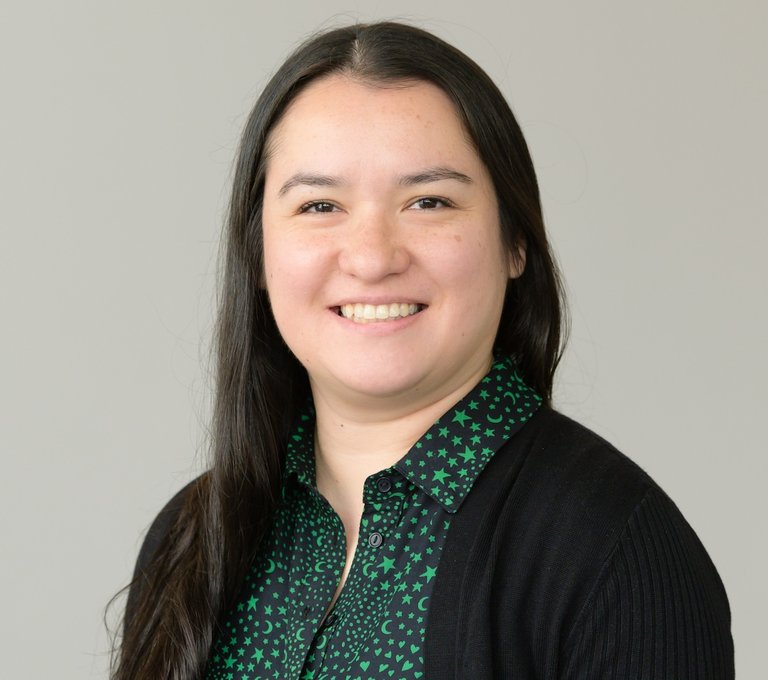 Headshot of a woman with black hair, a green shirt and black cardigan