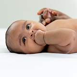 Photo of a baby laying on his back.