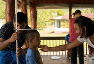 Man and a woman using a measuring stick to measure the height of a young boy