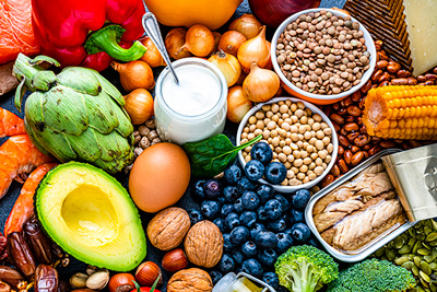 Wide shot of a pile of vibrant fruits, vegetables, nuts, fish, yogurt, and other healthy foods