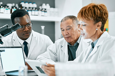 Group of scientists examine results from a microscope