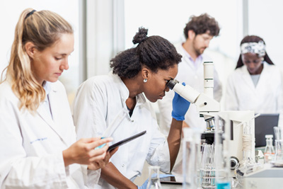 Research scientists in lab looking through a microscope