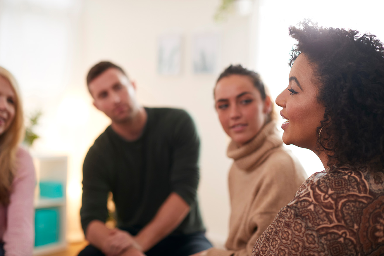young african american woman speaking to a group of diverse young people