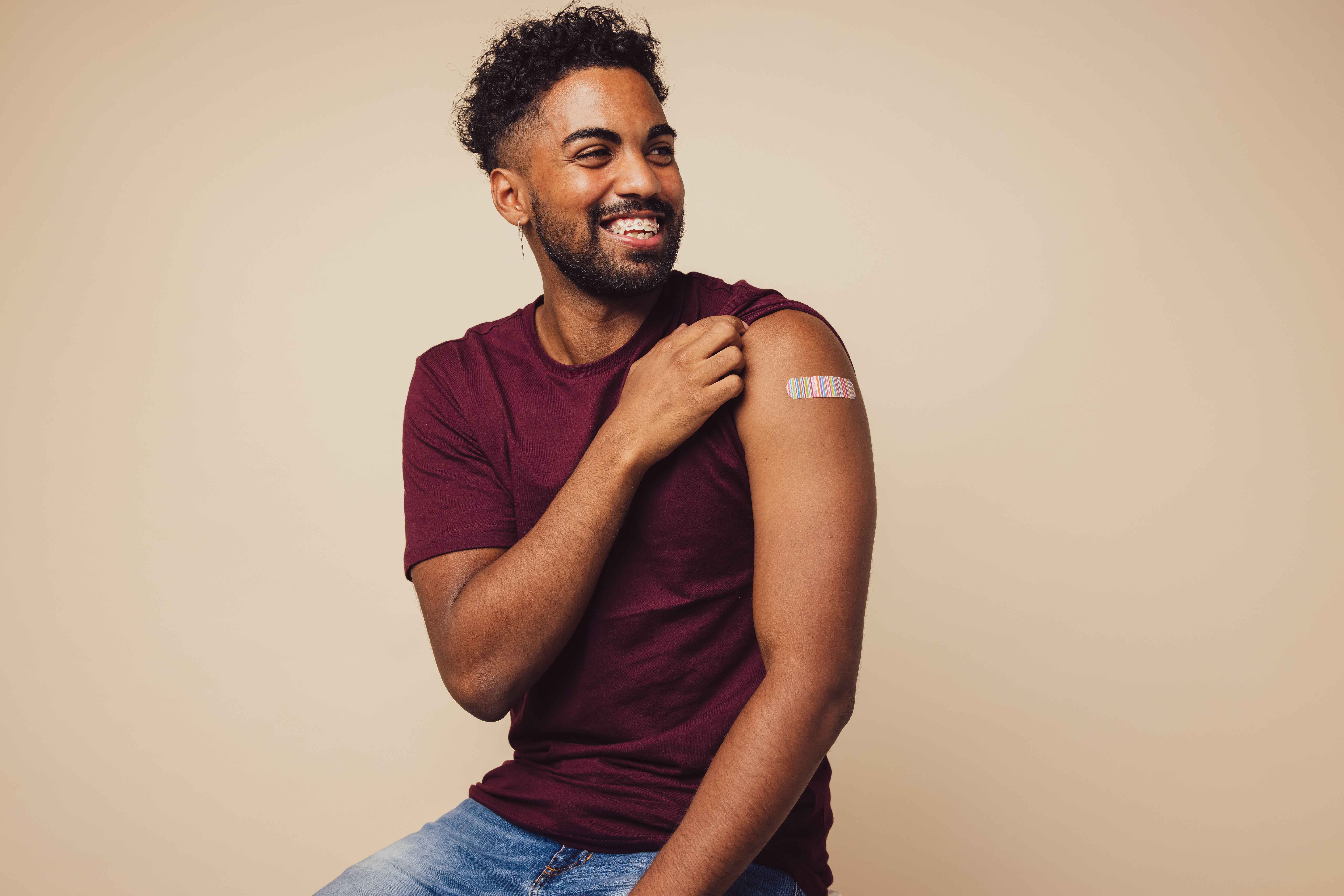 Young black man showing a band-aid on his arm, smiling
