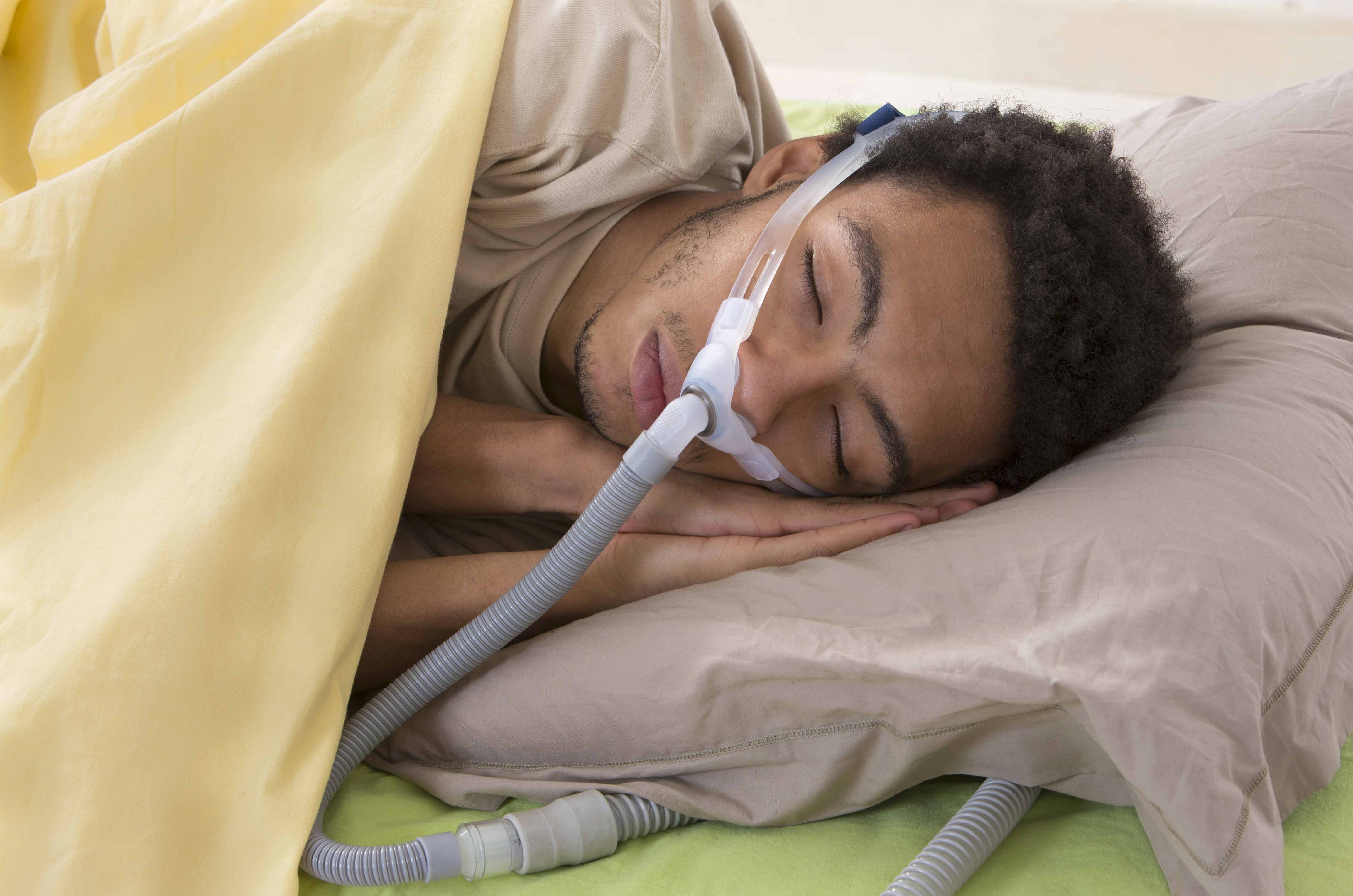 Black young man wearing a cpap machine while sleeping