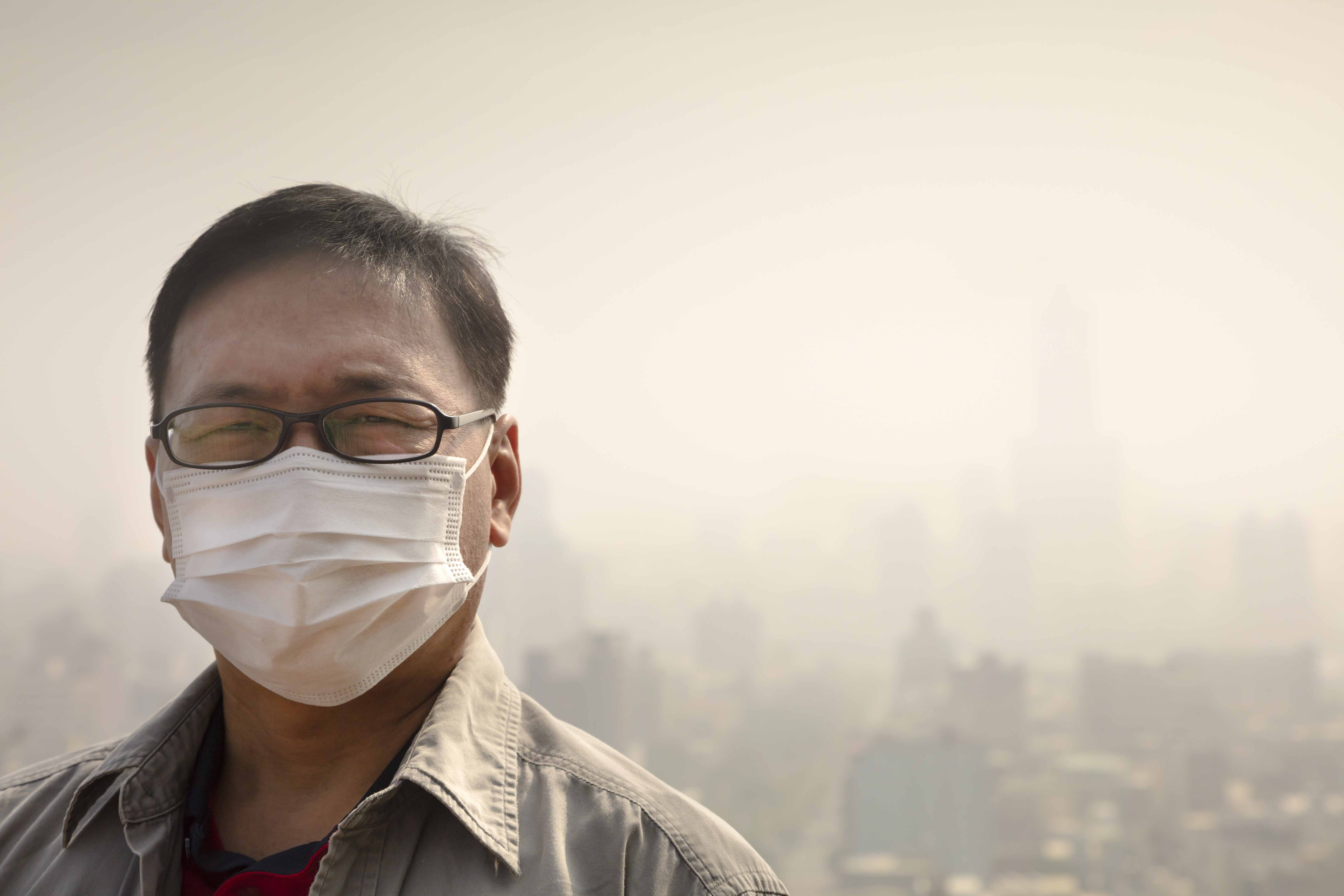Asian middle aged man wearing a mask. Hazy sky in the background