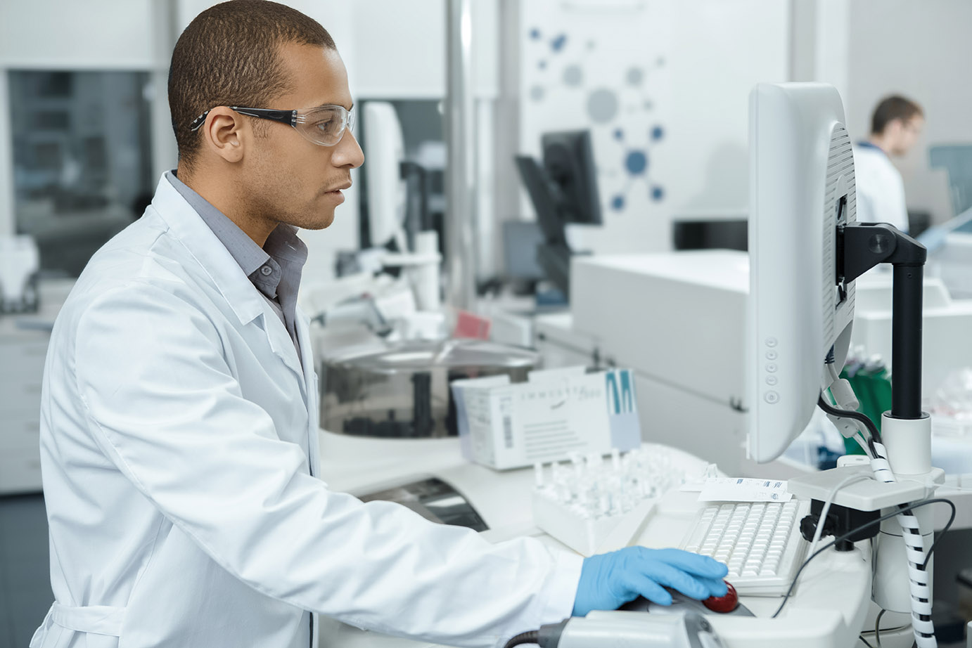 Young African american male laboratory technician using a computer working in the lab