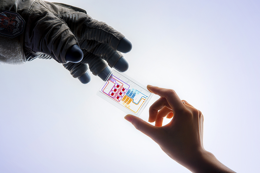 image of astronaut glove reaching to grab tissue chip from human hand.