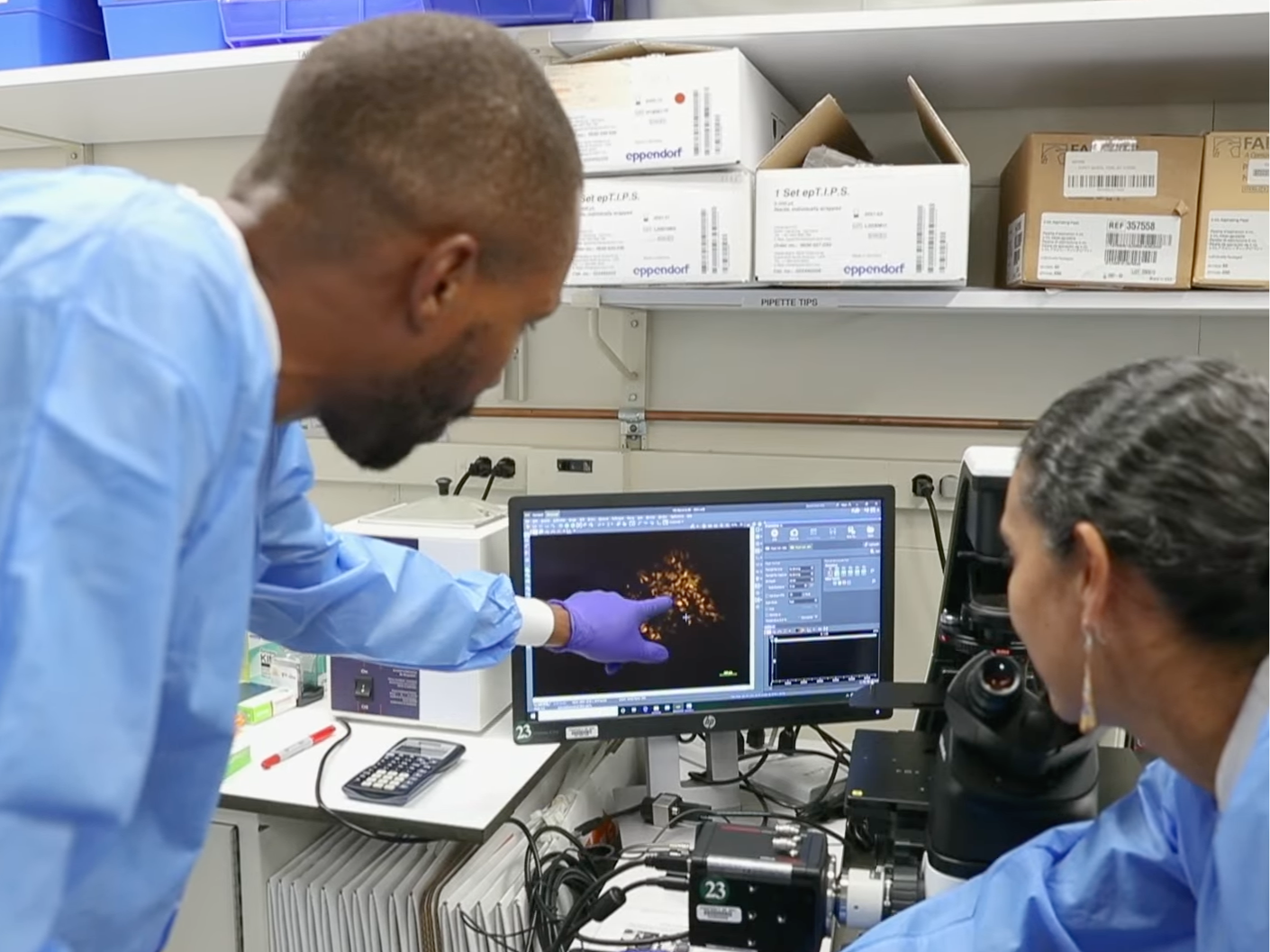 Two scientists in lab coats analyzing data on a computer screen.