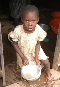 Young girl standing on the doorstep in a doorway holds a large bowl