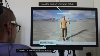 A person with a brain implant views a screen displaying a human avatar