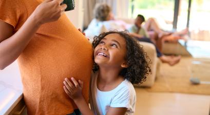 a young child hugging her pregnant mother.
