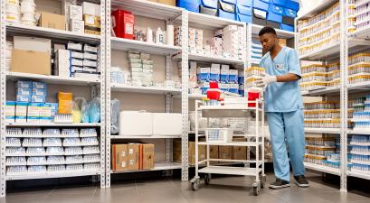 A healthcare worker organizes medical supplies on shelves in 
