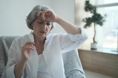 Middle-aged woman holds the back of her left hand to her forehead. 