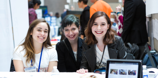Three women smiling, sitting behind a table